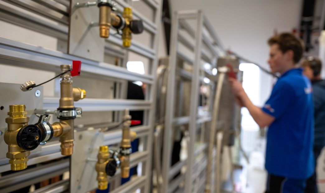 Ein Mitarbeiter in Ausbildung arbeitet an einer Anlage im Kompetenzzentrum der Innung Sanitär, Heizung und Klima Berlin.