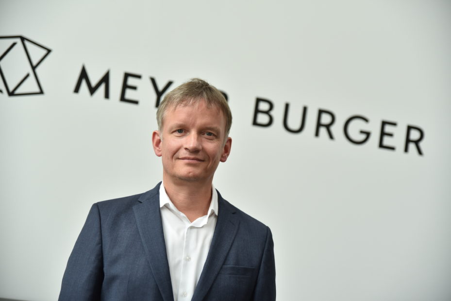 Der bisherige CEO des Solarunternehmens Meyer Burger, Gunter Erfurt, steht vor einem Schriftzug mit dem Unternehmensnamen.