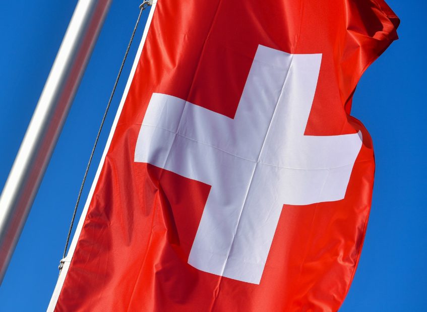 Die Nationalflagge der Schweiz, in der Baloise den Hauptsitz hat, weht vor blauem Himmel.