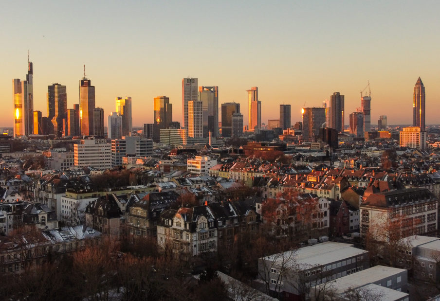 Das Licht der aufgehenden Sonne streift die Hochhäuser der Skyline von Frankfurt.