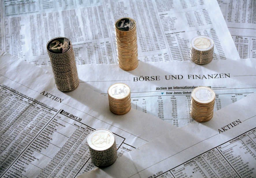 Berlin, Deutschland - Stapel von Euromuenzen auf Zeitungsseiten mit Boersenkursen und Aktiennotierungen. Symbolbild für Mythen an der Börse.