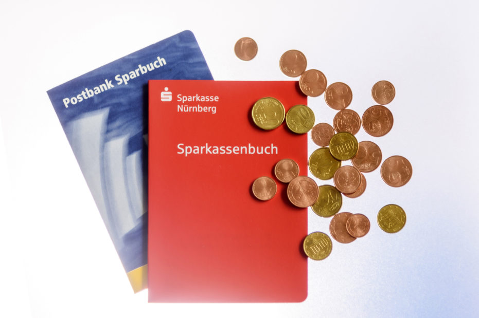 Sparbücher der Postbank und der Sparkasse mit Bargeld. Symbolbild Tagesgeld