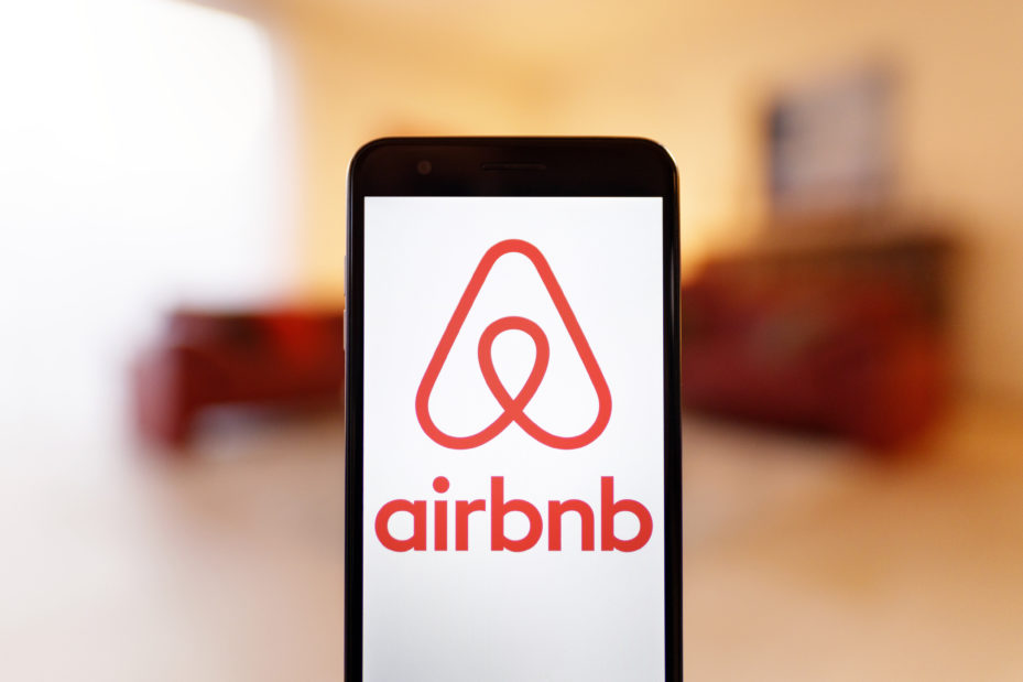 Das Logo des Wohnraumvermittlers Airbnb auf einem Mobiltelefon. Das Unternehmen, welches als Online-Marktplatz für Ferienwohnungen, Zimmer und Unterkünfte in Städten weltweit agiert, wurde durch die Corona-Pandemie hart getroffen. Trotz Verlusten im Corona-Jahr 2020 rechnet der Konzern mit einem Comeback der Reisebranche. (Themenbild, Symbolbild)