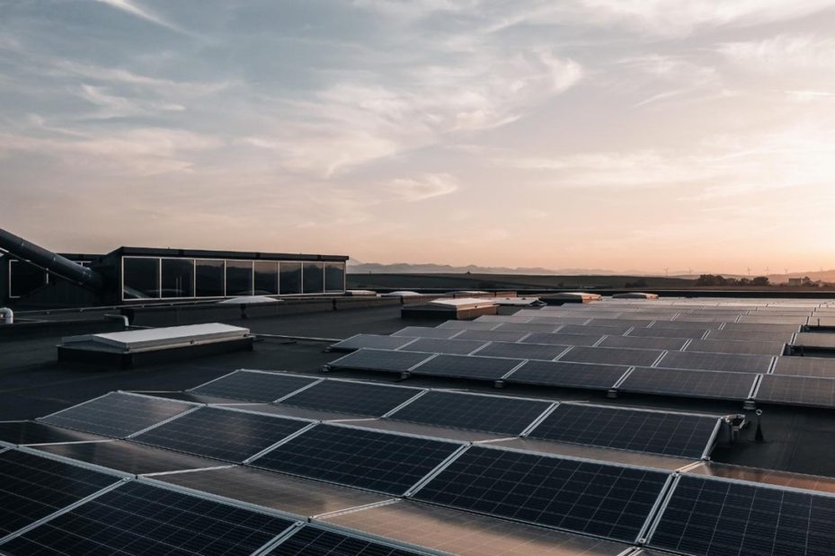 Solaranlage auf einem Industrieflachdach bei Sonnenuntergang mit leichten Wolken